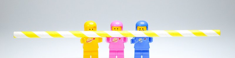 Drei Legofiguren halten einen Strohalm